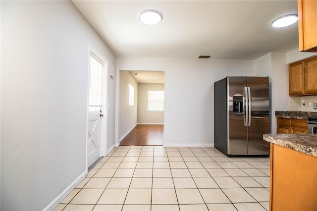 kitchen featuring light tile patterned floors, backsplash, and stainless steel refrigerator with ice dispenser