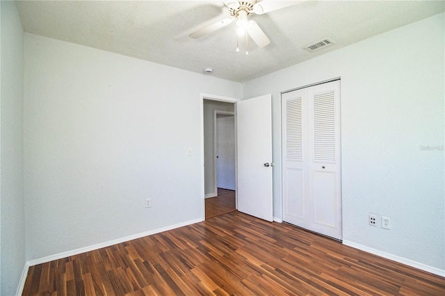 unfurnished bedroom with dark wood-type flooring, a closet, and ceiling fan