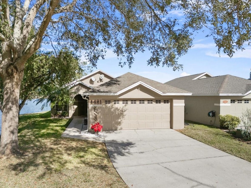 ranch-style home with a garage and a front lawn