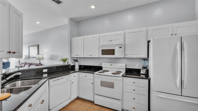 kitchen with light tile patterned flooring, sink, white cabinetry, dark stone countertops, and white appliances