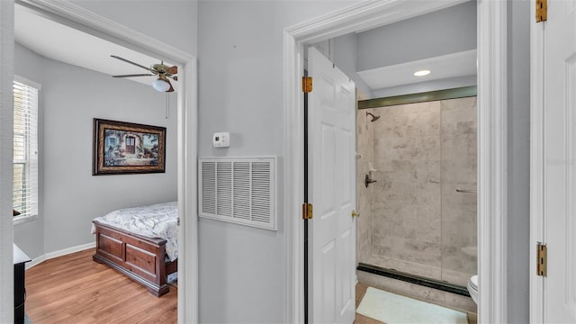 bathroom with hardwood / wood-style flooring, ceiling fan, toilet, and a shower with shower door