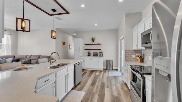 kitchen with sink, white cabinetry, pendant lighting, stainless steel appliances, and backsplash