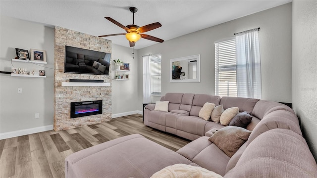 living room featuring ceiling fan, a fireplace, and light hardwood / wood-style flooring