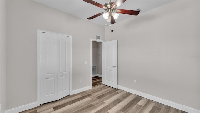 unfurnished bedroom with ceiling fan, a closet, lofted ceiling, and light hardwood / wood-style flooring