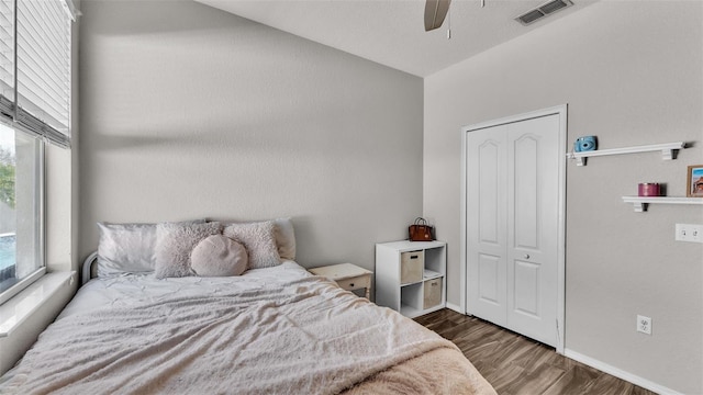 bedroom with dark wood-type flooring, ceiling fan, and a closet