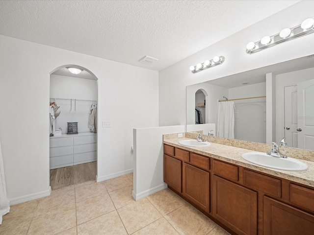 bathroom with tile patterned floors, vanity, curtained shower, and a textured ceiling