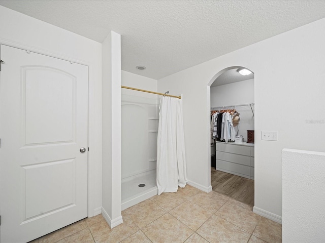 bathroom featuring walk in shower, tile patterned floors, and a textured ceiling