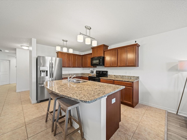 kitchen with sink, a breakfast bar, a kitchen island with sink, black appliances, and decorative light fixtures