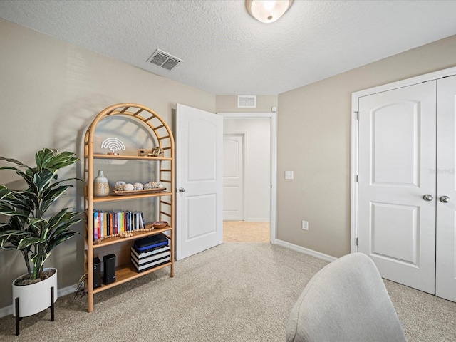 interior space featuring light carpet and a textured ceiling