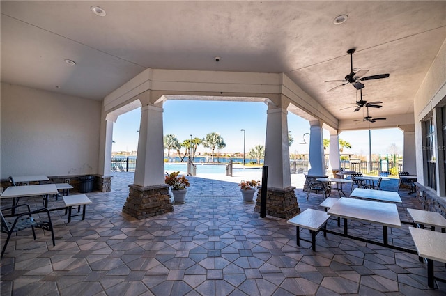 view of patio with a water view, a community pool, and ceiling fan