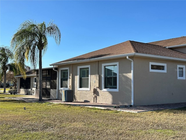 view of front of home with central AC unit, a patio area, a front lawn, and a sunroom