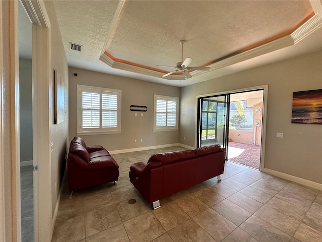 living room with a raised ceiling, light tile patterned floors, a textured ceiling, and ceiling fan