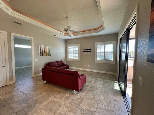 living room featuring ceiling fan, ornamental molding, a raised ceiling, and a textured ceiling