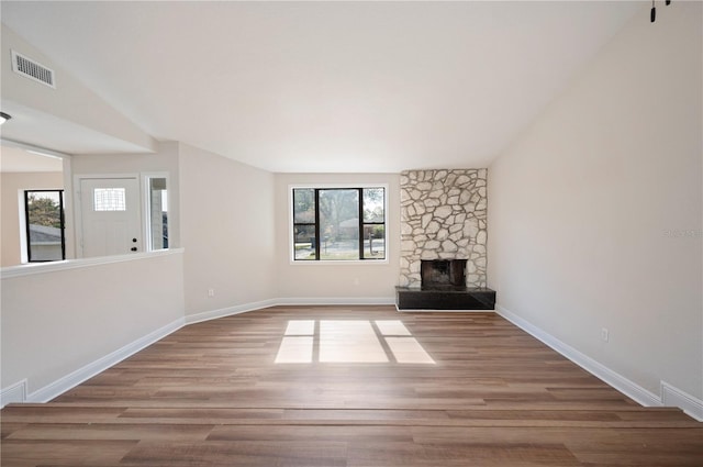 unfurnished living room featuring lofted ceiling, a fireplace, and light hardwood / wood-style floors