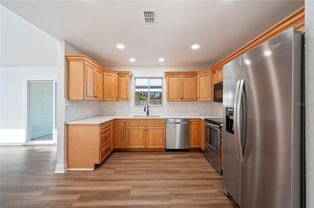 kitchen with stainless steel appliances, light hardwood / wood-style floors, sink, and backsplash