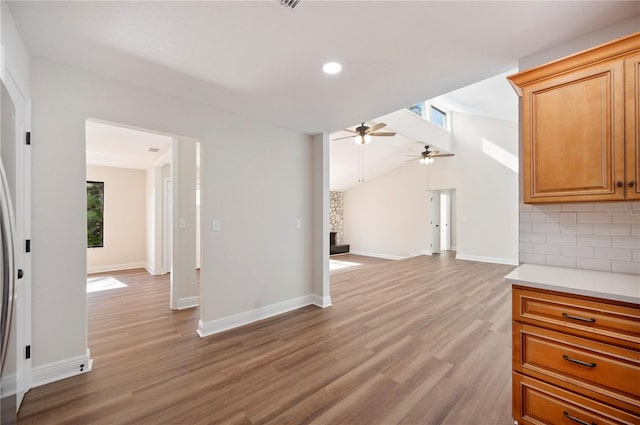 unfurnished living room with vaulted ceiling, light hardwood / wood-style floors, and ceiling fan