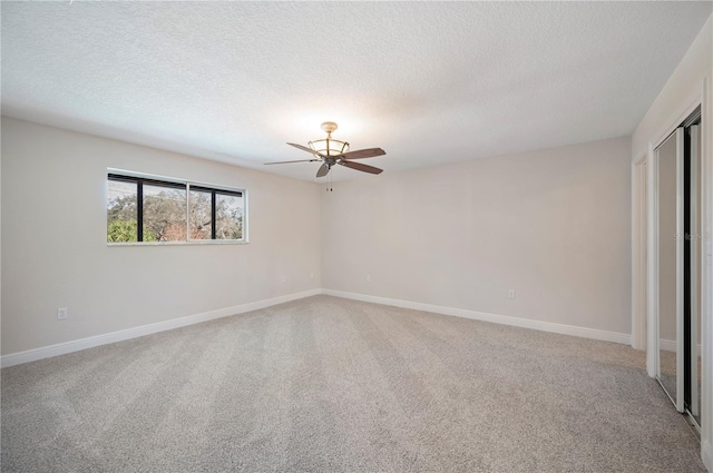 carpeted spare room with a textured ceiling and ceiling fan