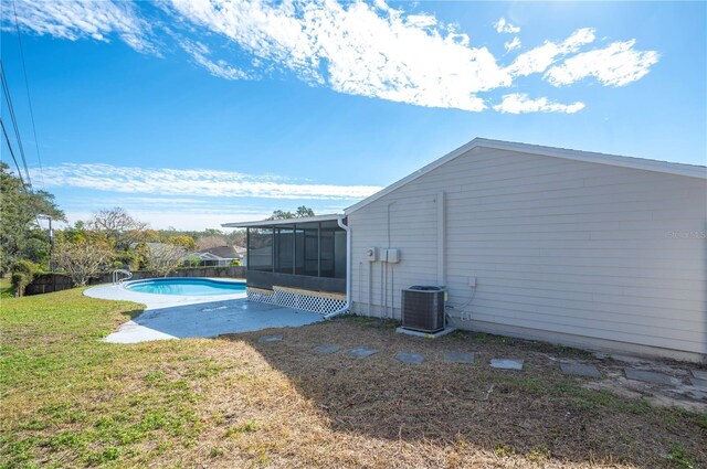 view of pool with cooling unit, a yard, and a sunroom