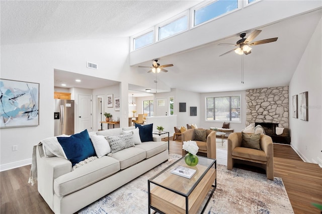 living area featuring a ceiling fan, wood finished floors, high vaulted ceiling, a fireplace, and baseboards