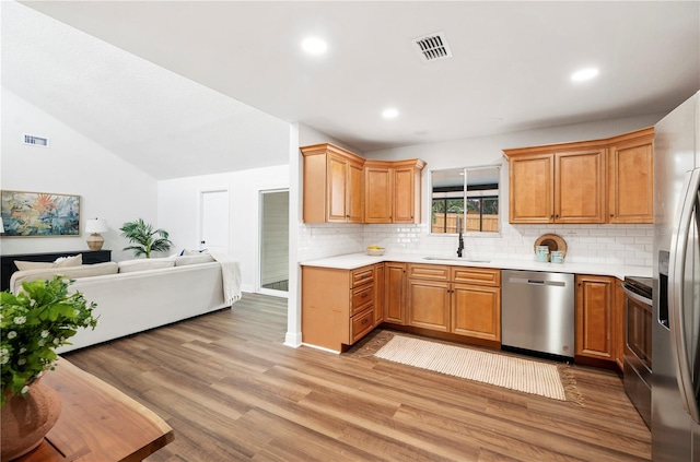 kitchen with stainless steel appliances, a sink, open floor plan, decorative backsplash, and light countertops
