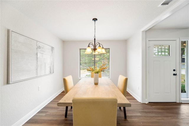dining space featuring a chandelier, dark wood-type flooring, and baseboards