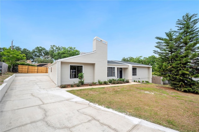 mid-century inspired home with a chimney and concrete driveway