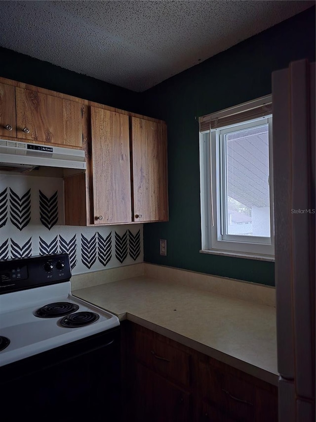 kitchen featuring fridge, decorative backsplash, a textured ceiling, and electric range