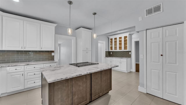 kitchen with a kitchen island, white cabinets, hanging light fixtures, light stone countertops, and black electric cooktop