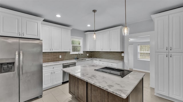 kitchen with decorative light fixtures, white cabinetry, backsplash, stainless steel appliances, and light stone countertops