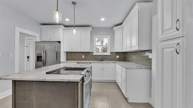 kitchen with pendant lighting, stainless steel appliances, a center island, and white cabinets