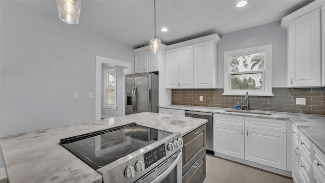 kitchen featuring appliances with stainless steel finishes, sink, hanging light fixtures, and white cabinets