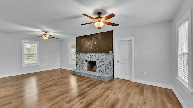 unfurnished living room with ceiling fan, a fireplace, and light hardwood / wood-style flooring