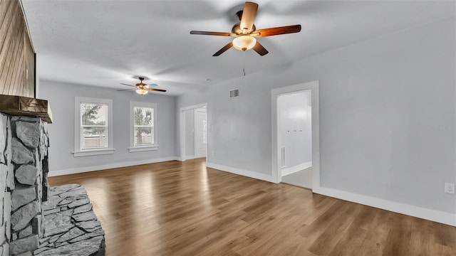 unfurnished living room featuring ceiling fan, a fireplace, and light hardwood / wood-style floors