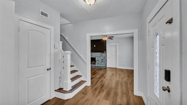 foyer entrance featuring a stone fireplace and light hardwood / wood-style floors