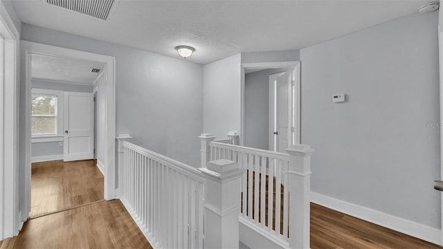 hall with hardwood / wood-style flooring and a textured ceiling