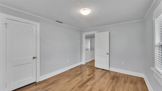 unfurnished bedroom featuring light hardwood / wood-style flooring, ornamental molding, and a textured ceiling