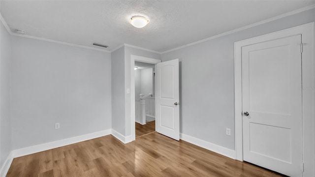 unfurnished bedroom with ornamental molding, a textured ceiling, and light wood-type flooring