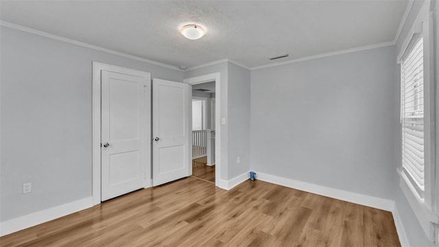 unfurnished bedroom with ornamental molding, a textured ceiling, and light wood-type flooring