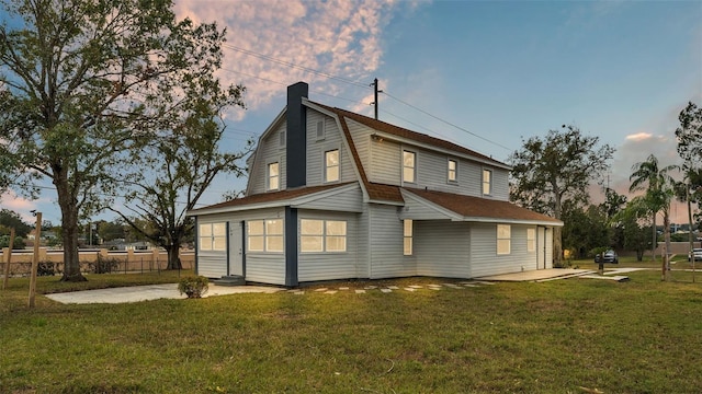 back house at dusk featuring a lawn