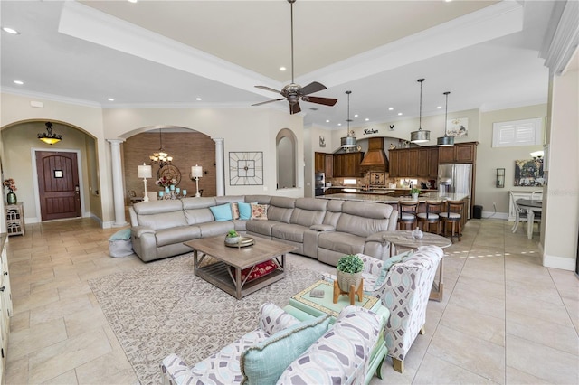 living room featuring decorative columns, crown molding, and a raised ceiling