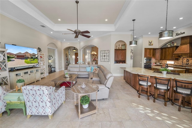 living room with a tray ceiling, ornamental molding, and ceiling fan