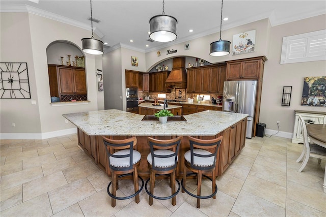 kitchen with a spacious island, stainless steel appliances, light stone countertops, and hanging light fixtures