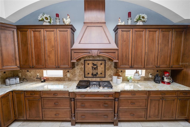 kitchen with stainless steel gas stovetop, light stone countertops, vaulted ceiling, and decorative backsplash