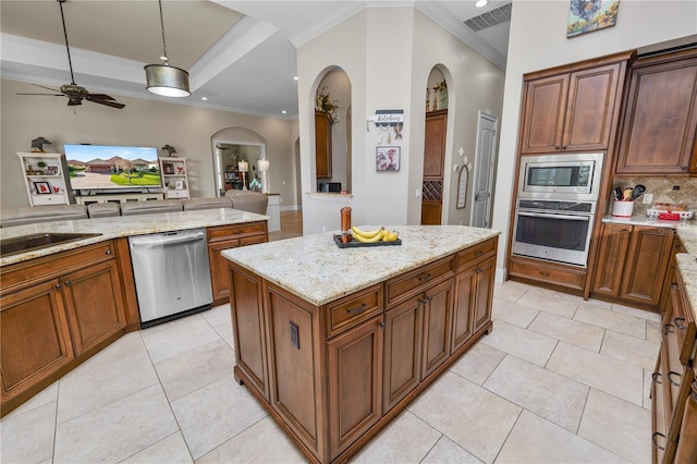 kitchen featuring light tile patterned floors, appliances with stainless steel finishes, hanging light fixtures, a center island, and light stone countertops