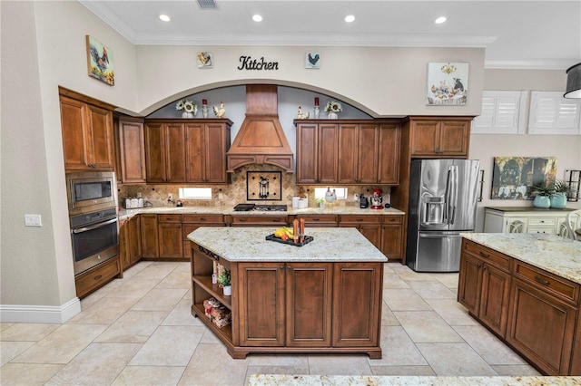 kitchen with decorative backsplash, a center island, stainless steel appliances, light stone countertops, and custom range hood