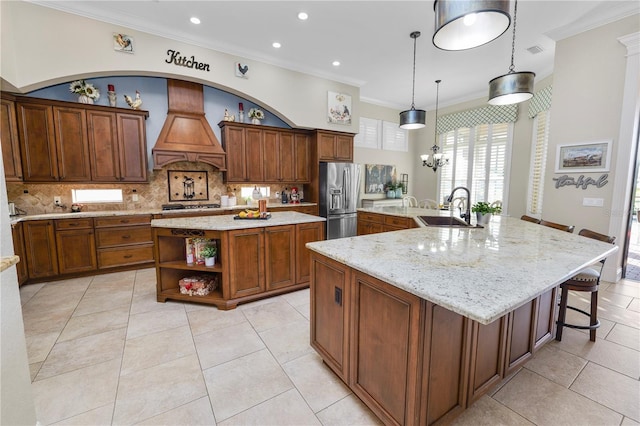 kitchen with sink, premium range hood, hanging light fixtures, stainless steel appliances, and a spacious island