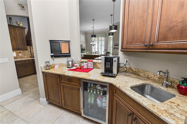 kitchen with sink, hanging light fixtures, wine cooler, light stone counters, and ornamental molding