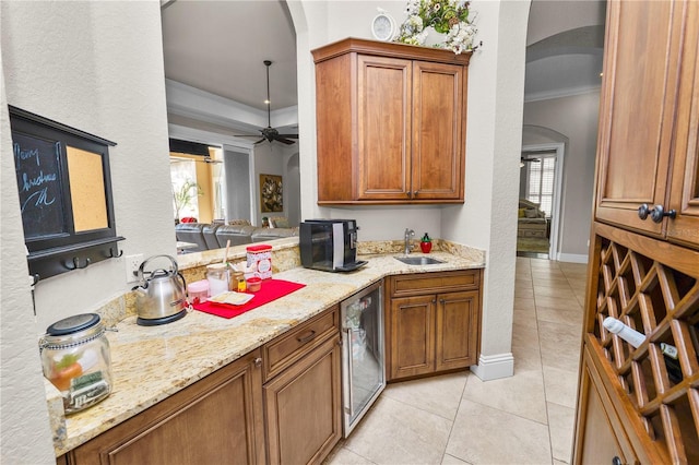 kitchen featuring sink, crown molding, light tile patterned floors, wine cooler, and light stone counters