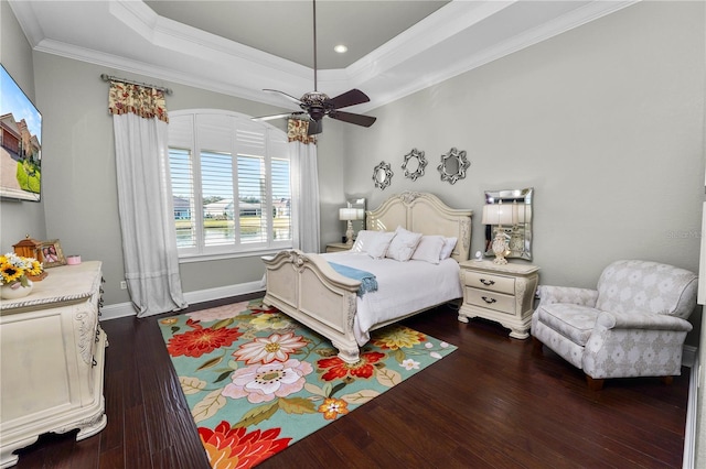 bedroom with crown molding, dark hardwood / wood-style floors, ceiling fan, and a tray ceiling