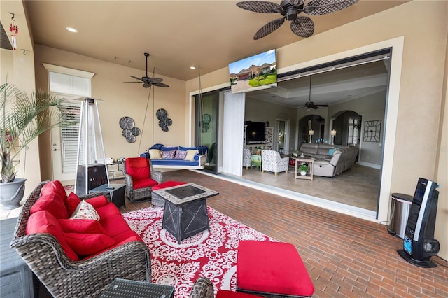 view of patio / terrace featuring ceiling fan and an outdoor living space with a fire pit